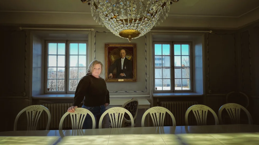 Susann Andreasson är husets ägare idag. Tavlan bakom henne visar Järnhandlarvillans ursprungliga ägare, TH Jansson (1878– 1940). 