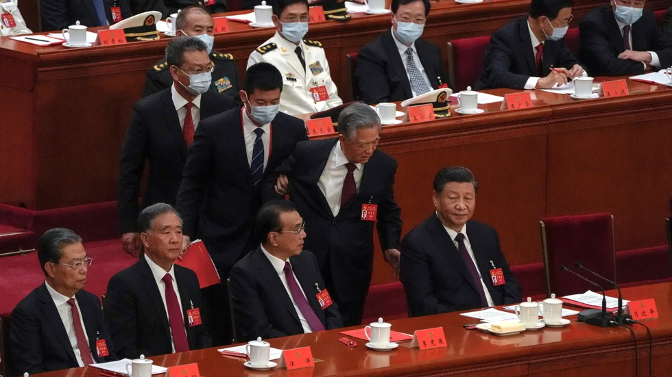 Hu Jintao, Kinas president mellan 2003 och 2013, förs bort från Folkets stora sal i Peking under partikongressens avslutningsceremoni. President Xi Jinping sitter längst till höger.