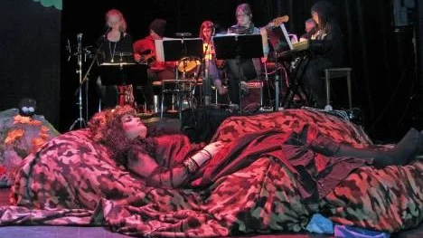 Skogens drottning Titania (Elin Brännmark) sover skönt till tonerna från teaterorkestern och duktiga sångerskan Josefin Westbom (till vänster).