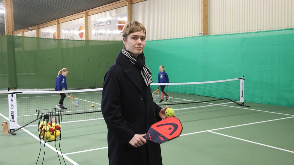 Axel Ahlström, styrelseledamot i Enköpings Tennisklubb, visar den nya pickleballbanan som också kan användas till minitennis något som Greta och Ida i bakgrunden gör.