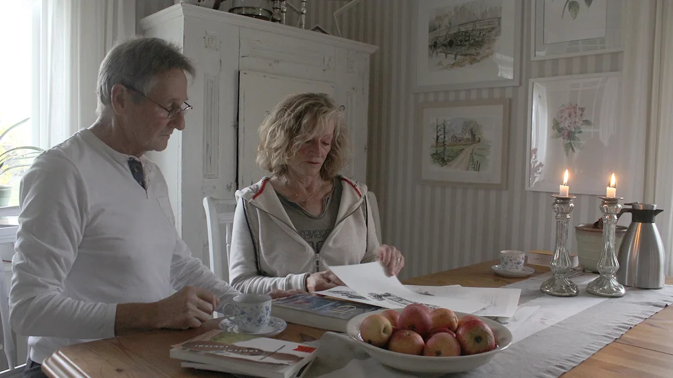 Marten och Annelie Petersen vid köksbordet i den egna villan på Gamla Garvaregården, utanför Mörlunda. Marten är aktuell med romanen "Tjejen från Tveta", som Annelie gjort illustrationerna till. På väggen hänger några av de tavlor hon målat.