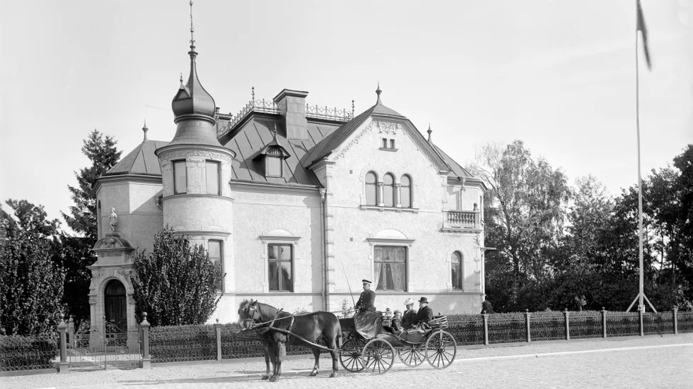 Den Asklundska villan färdigställdes 1894. Byggherre var tobaksfabrikören Ernst Asklund, som sannolikt ses i vagnen. Tidningen Östgöten beskrev villan som en av stadens nättaste byggnader hållen i på samma gång en egendomlig och behaglig villastil. Bilden är tagen 1902.