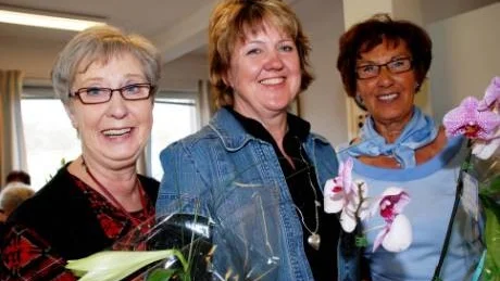 Annika Olsson, samordnare på Frivilligcentralen (i mitten) gratulerar Birgitta Edlund och Berith Nordh i samband med Drop-in Källans ettårsjubileum.
