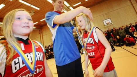 Elin Thun och Alice Olsson ur föreningssegraren Gladans yngsta lag får sina medaljer av LF Baskets Gustav Nyström.