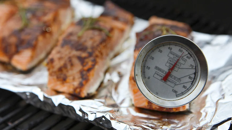 Med en vanlig stektermometer kollas kärntemperaturen hos fisken innan den lyfts från grillen.