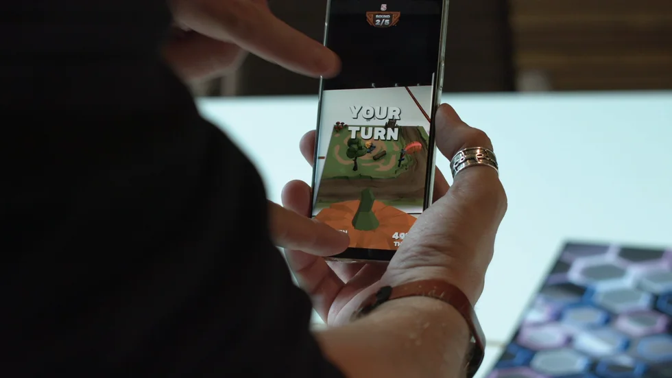 I Lazer Wolf Studios spel använder spelarna Augumented Reality i sina mobila enheter för att tillsammans interagera i en virtuell värld med en spelbräda som fysiskt ankare i verkligheten.