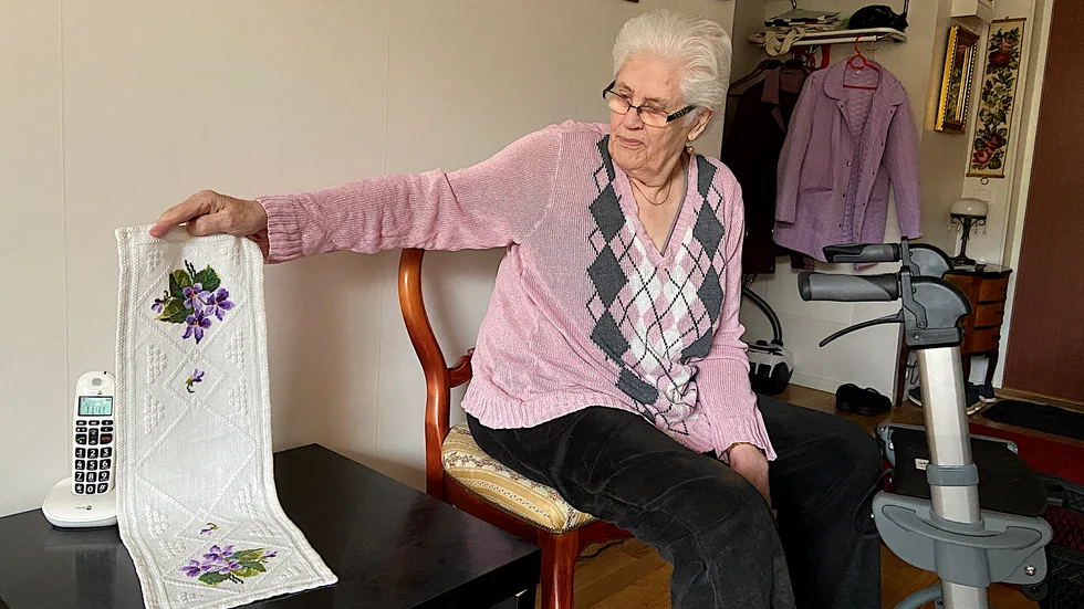 Sonja Sundvall med en av få handbroderade dukar som hon nu äger. Dukarna som låg framme har lämnats kvar.