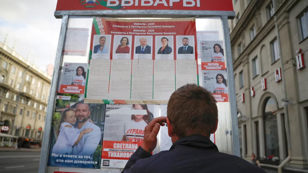 En man står framför en valaffisch i Minsk, Belarus.