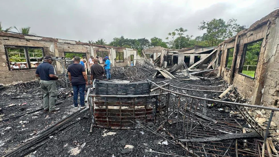 Invånare utanför resterna av den brandskadade sovsalen i Guyana.