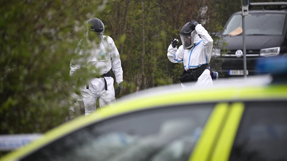 Polis och kriminaltekniker på plats vid en utbränd bil på en parkering i Lomma kommun på söndagen. I bilen hittas något som polisen misstänker är en människokropp.