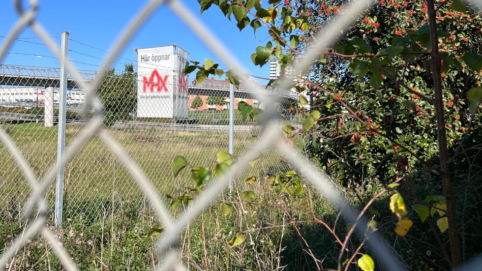 Långt bort skymtar hamburgerkedjans reklampelare "Här öppnar Max", men fastigheten är fortfarande orörd bakom ett högt staket. 