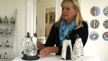 Här plockar Anette Berglund fram en del av produktionen som är mer figurativ. I bakgrunden syns fler av hennes olika skålar och burkar samt en del av den vägghängda keramiken.