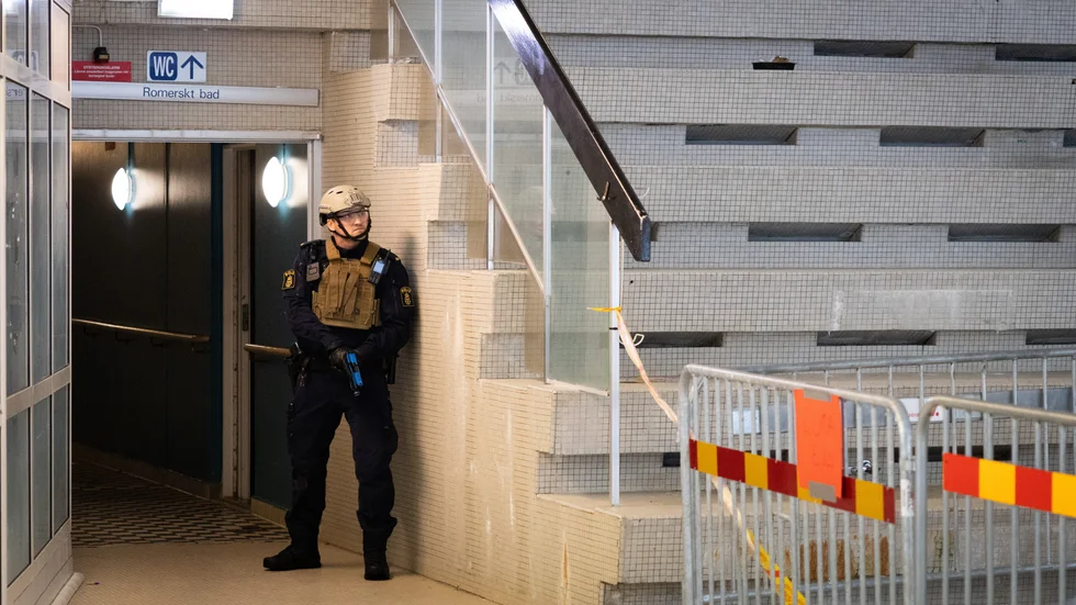 En polis vaktar i hörnet i rummet där den stora bassängen är i gamla simhallen.