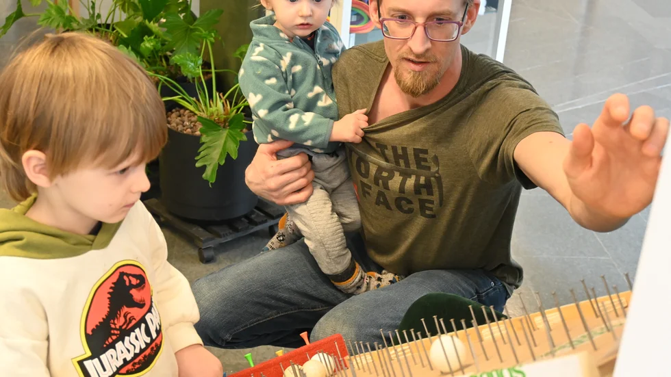 Zack Lang visar hur en plinko-maskin fungerar för sina barn Viggo och Kayden Pyyny Lang
