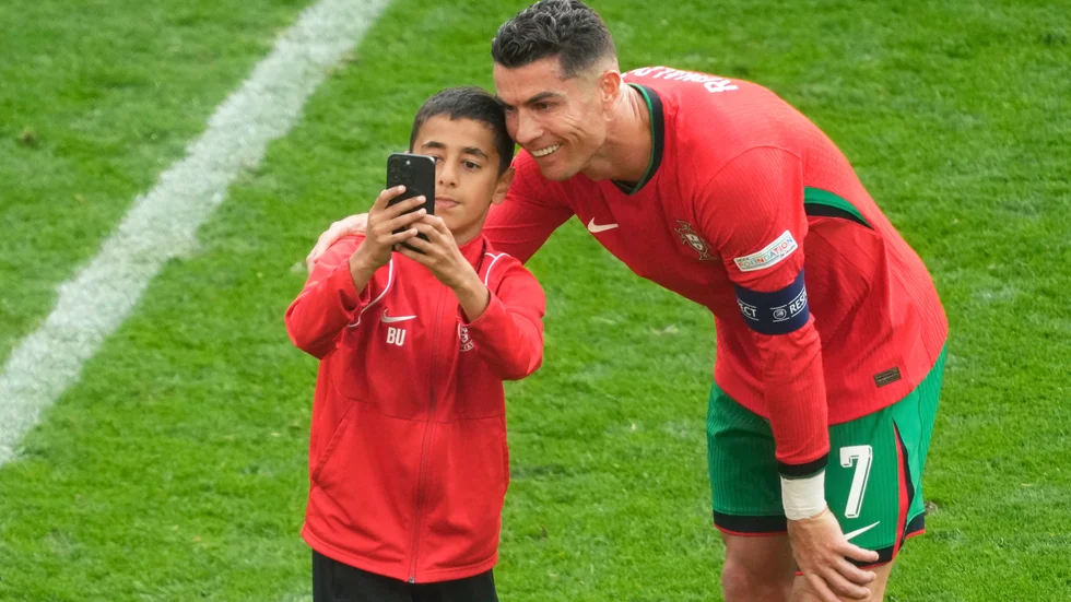 Cristiano Ronaldo tar en selfie med en ung planstormare.