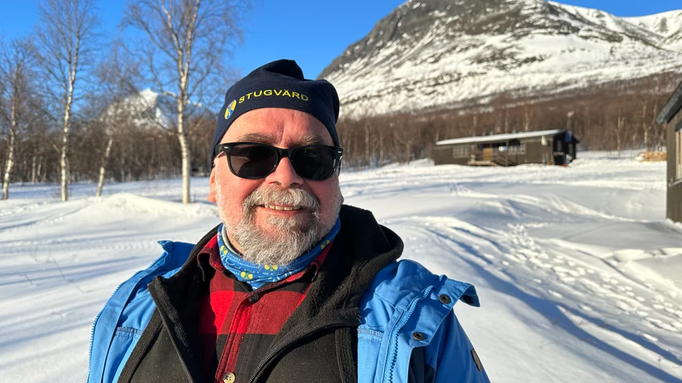 Ola Borin vid foten av fjället Tarrekaise. Gäststugan för turisterna syns i bakgrunden.