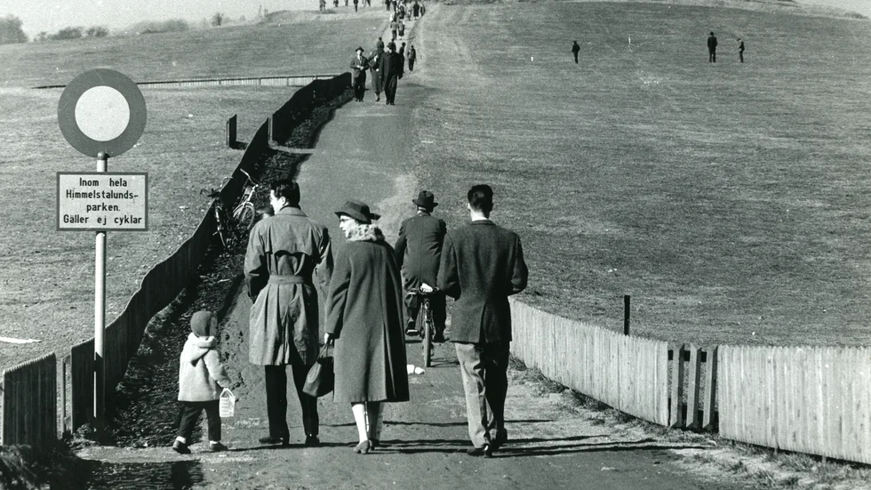 Då. Vårens ankomst lockar ut Norrköpingsborna i slutet av mars 1959. Att promenera på Himmelstalund var ett folknöje. Den röda ladan på toppen brann ned 1977 och trästaketet utmed gångbanan är också sedan länge borta.