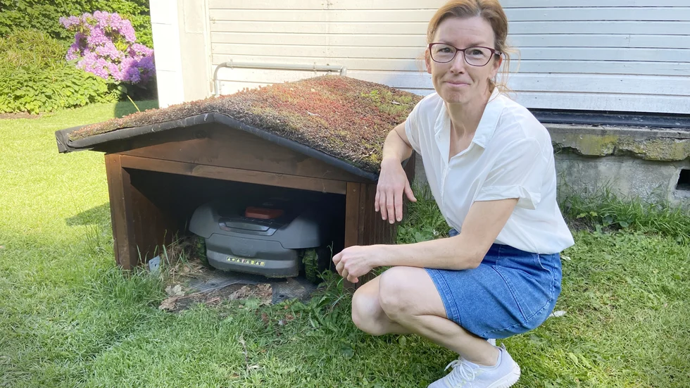 "Robotgräsklipparna gör stor nytta för kommunen och oss invånare", säger Kristina Svinhufvud, här vid det lilla hus som maskinen söker laddning i och bor i nattetid.