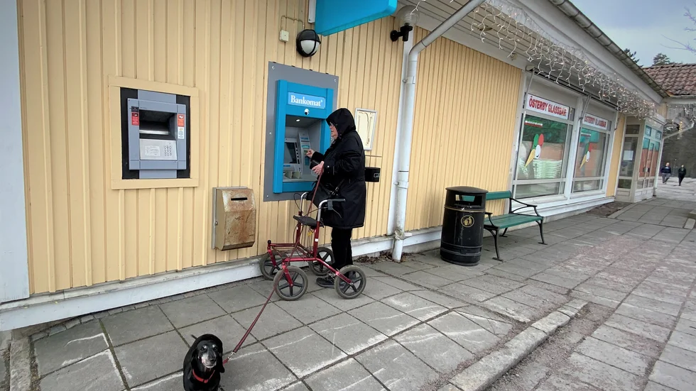 Solbritt Persson tar ut kontanter i Österbybruk. Med på bilden är taxen Sotis. "Bankkontor behövs, man vill ju kunna gå in och fråga saker."