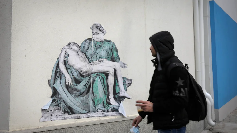 En man passerar gatukonst föreställande en modifierad variant av Michelangelos skulptur Pietà utanför ett sjukhus i Bulgariens huvudstad Sofia. Bilden är från den 7 februari.