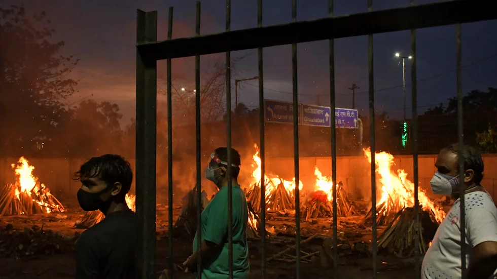 Många indier som avlidit med covid-19 dumpas i Indiens stora vattendrag. Här säger människor farväl till sina anhöriga vid ett provisoriskt krematorium i huvudstaden New Delhi den 6 maj. Arkivbild.