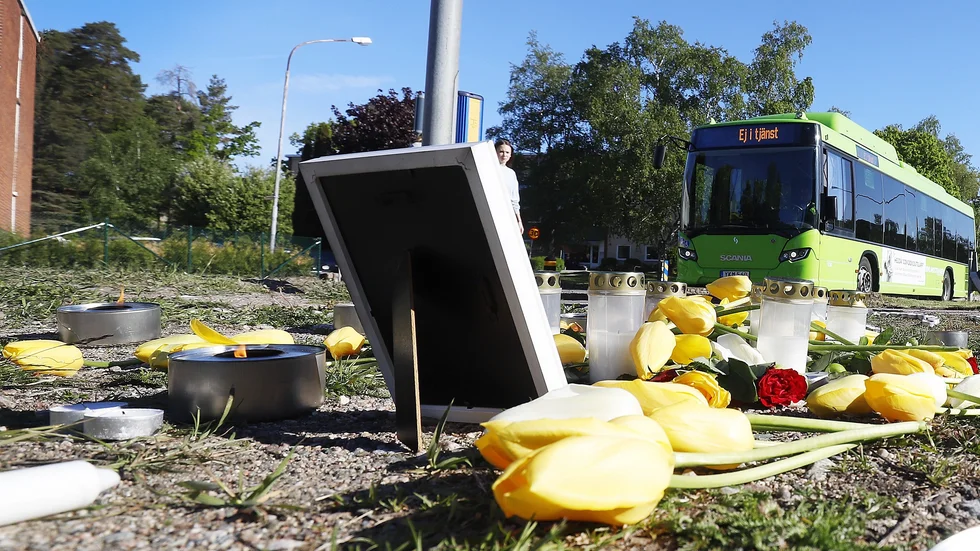 Raden av ljus och hägen med blommor på mordplatsen.
