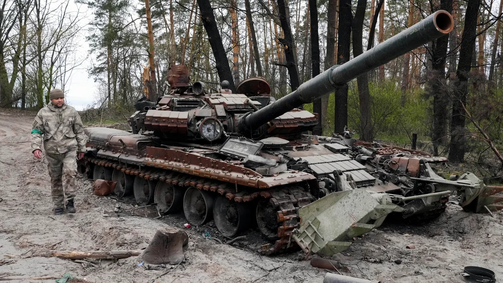 En ukrainsk soldat går förbi en rysk stridsvagn efter strider i Mosjtjun, nära Kiev. Bild från 19 april.