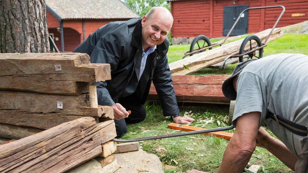 Tradition. Johan Widerström, vd, Kinda-Ydre sparbank, lägger ett mynt mellan det första och andra varvet timmer.