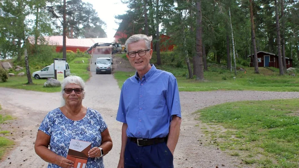 Britt Sjögren och Jangunnar Hjalmarson från församlingens programråd med sommarens program. I bakgrunden syns den nya kyrkobyggnaden.