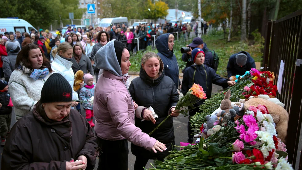 Människor lägger ner blommor utanför den skola i staden Izjevsk där minst 17 personer dödades.
