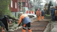 Pågående spårarbete vid smalspårets järnvägsövergång i Verkebäck. I kväll öppnas åter väg 807 för trafik. Daniel Niklasson, ordförande i Tjustbygdens Järnvägsförening, till vänster, deltar i grävarbetet tillsammans med Vägverkets personal. Foto: MARGARETA LJUNGBLAD