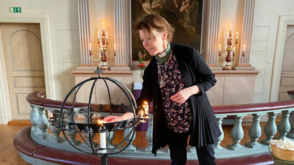 Diakon Lena Selin tänder ljus i Malå kyrka.