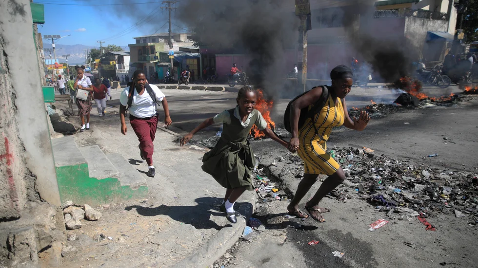 En kvinna och hennes dotter springer förbi en avspärrning på en gata i Haitis huvudstad Port-au-Prince den 26 januari.