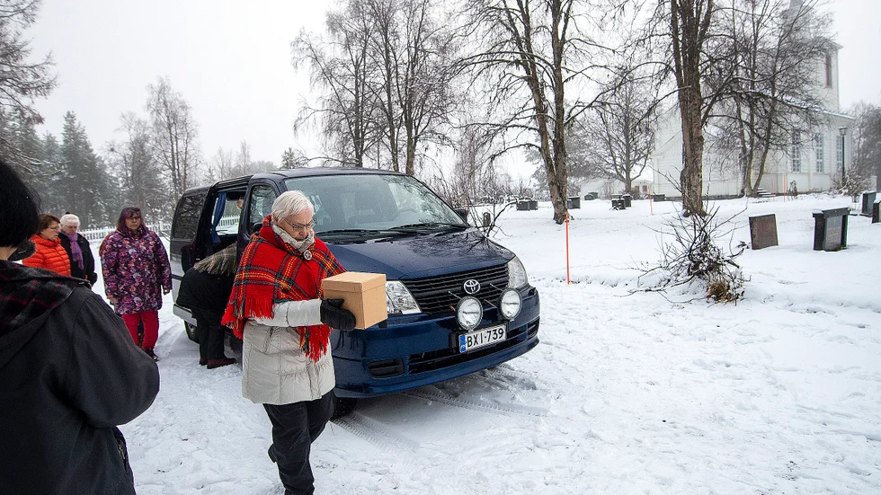 Lådorna transporterades i en svart bil av samemuseet Siida från finska Enare till Muodoslompolo. Här en anhörig, 79-åriga Rauha Ryynänen, bärandes ett av de 23 kranierna som ska återbegravas på ödekyrkogården i nordöstra Pajala.