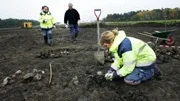 Annika Blom putsar fram stenar vid ett av stolphålen. Grävledare är Kerstin Åberg och Dan Fagerlund.