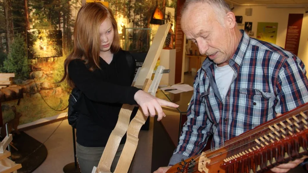 Bygga nyckelharpa. Emilie Johansson, 15 år, frågar Esbjörn Hogmark om en detalj på en färdig nyckelharpa.