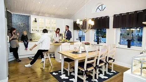 Fyra fönster ger köket mycket ljus, en lyx som kräver en köksö för att kompensera den förlorade bänkytan. Ödlan Snuggels har sitt terrarium på hedersplats vid matbordet. På bilden syns också Moa, Moas pojkvän, Emilia, Carola och Jonas.