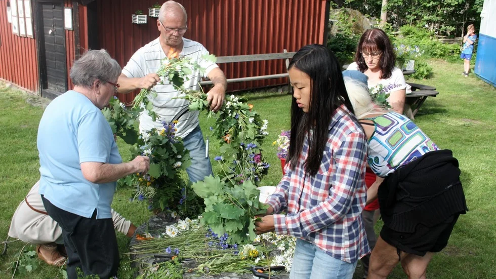 Här hjälper alla till med att binda vackra kransar till midsommarstången. Foto: Annika Stagård