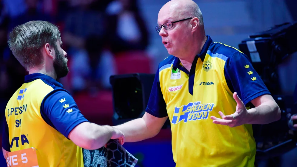 Sveriges Jon Persson peppas av förbundskapten Ulf "Tickan" Carlsson under matchen mot Kinas Ma Long i semifinalen under lag-VM i bordtennis i Halmstad  Arena.