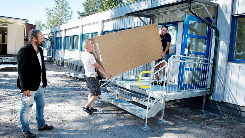 Flyttar. Johan Rönnberg tittar till modulen medan Fredrik Grabbe, Input, och Anders Pettersson, slöjdlärare och skoltekniker, bär in möbler. Foto: Annika Eriksson.