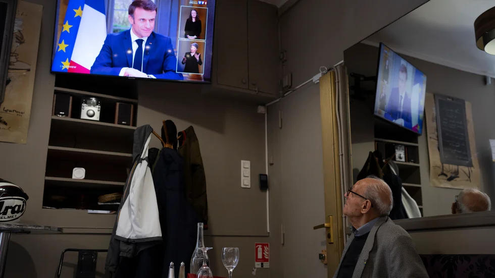 En man sitter på en krog i Marseille och följer den direktsända intervjun med president Macron.