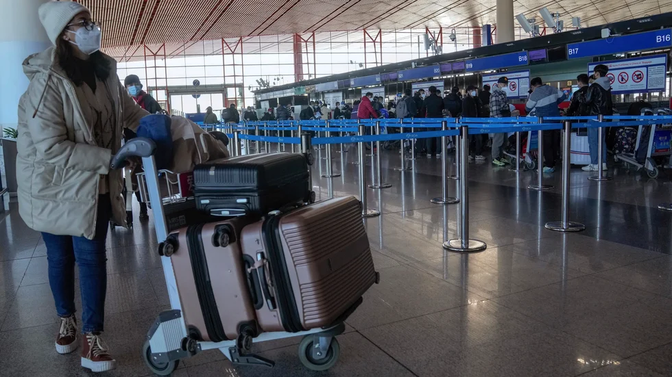 En resenär ska precis checka in på Pekings internationella flygplats under torsdagen. Nu vidtar en rad länder åtgärder för resenärer från Kina med anledning av den ökade smittspridningen i landet.