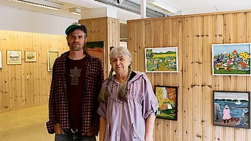 Åskar Lilja och Irene Örbäck framför Irenes färgglada målningar.