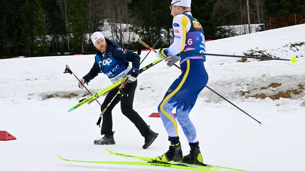 Sveriges landslagschef Anders Byström ger Jens Burman nya skidor efter kraschen i skiathlonloppet.