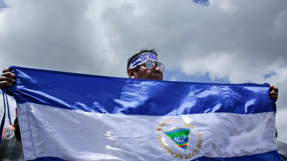 En demonstrant håller upp i flagga under en demonstration för stöd för journalister i Nicaragua 2018.