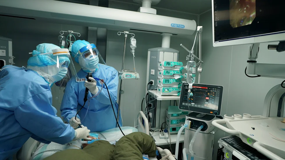 Vårdanställda i Wuhan undersöker en patient på ett fältsjukhus. Arkivbild.
