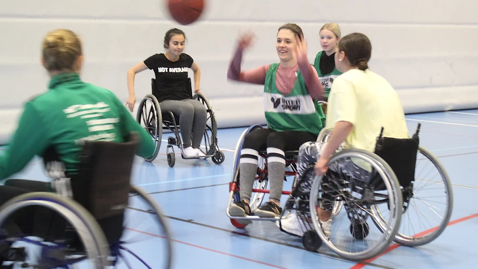 Alma persson i 9C på Albäcksskolan (i mitten) fick chansen att prova på rullstolsbasket genom att Ewa Anemyr från Smålands Parasportsförbund deltog i dagen.