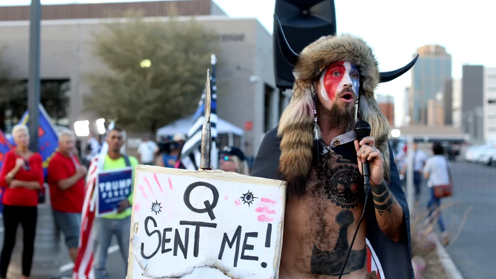 En Qanon-anhängare talar till anhängare till den tidigare presidenten Donald Trump i Phoenix i november. Samme man deltog i stormningen av USA:s kongress i januari.