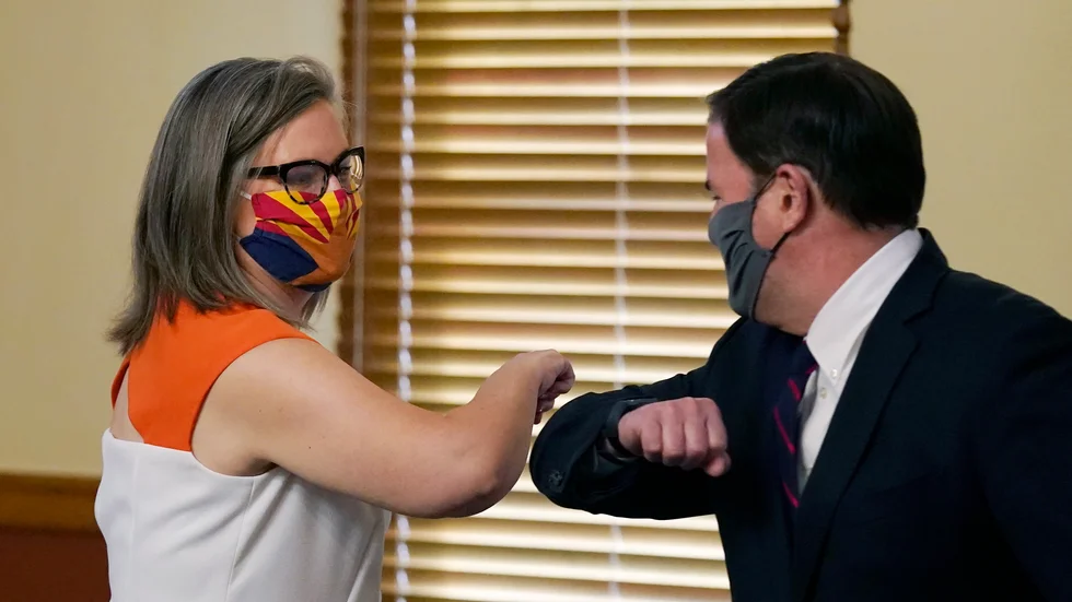 Arizonas delstatssekreterare, demokraten Katie Hobbs, nuddar armbåge med guvernören tillika republikanen Doug Ducey. De är överens om att valet där gått rätt till.