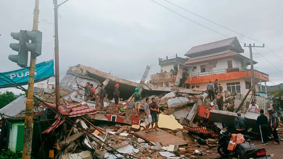 Boende inspekterar ett raserat hus i Mamuju på västra Sulawesi i Indonesien.
